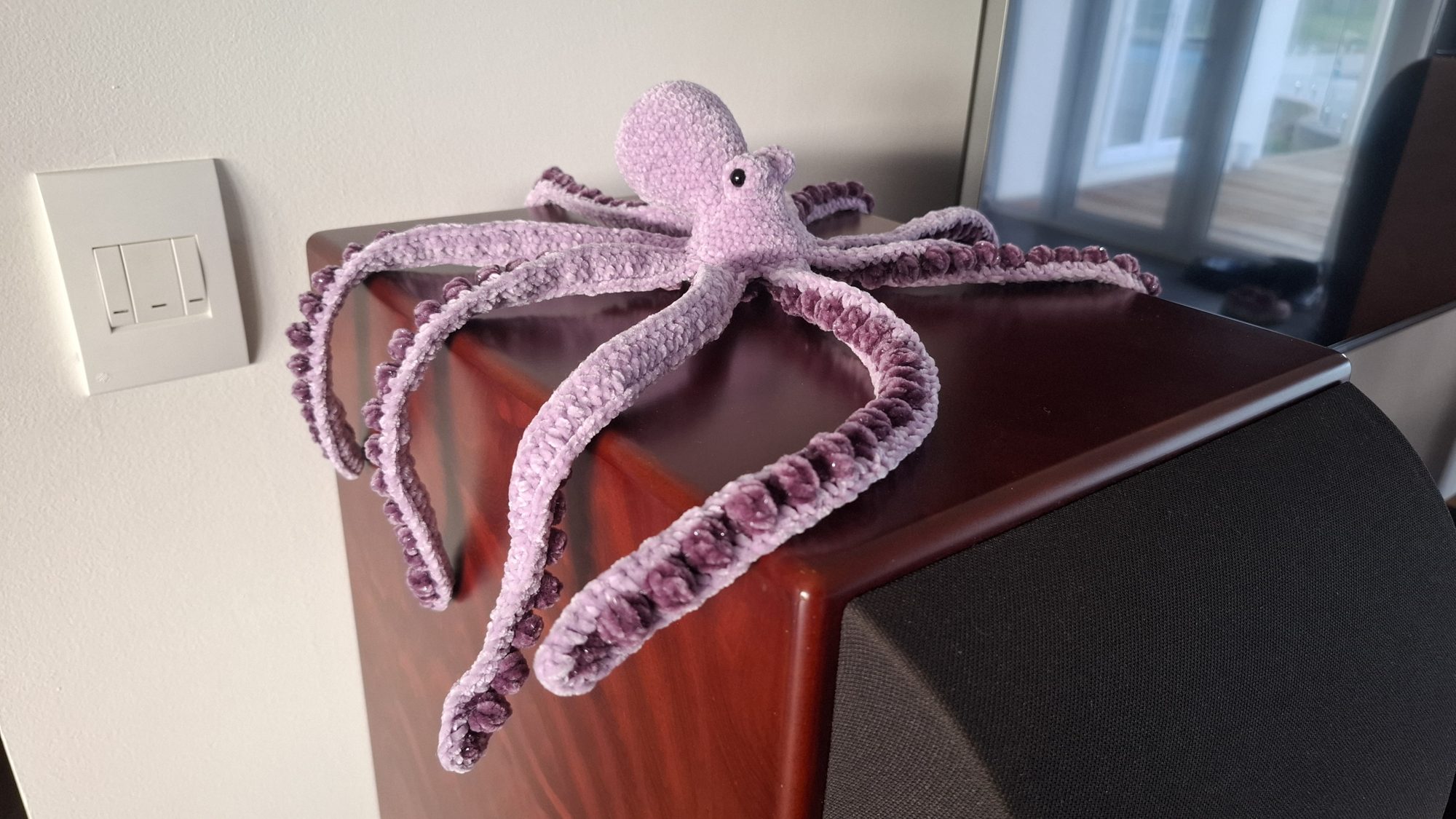 A large purple chenille crocheted octopus with curling tentacles