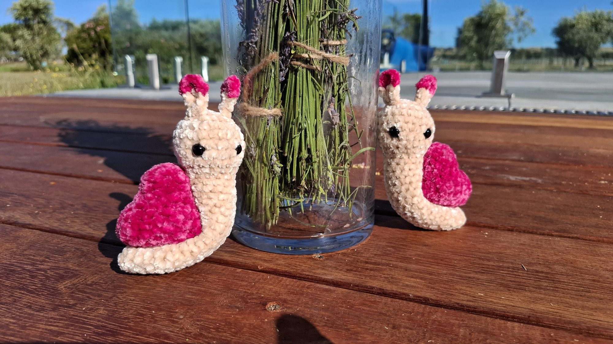 Two beige velvet crocheted snails with pink heart-shaped shells